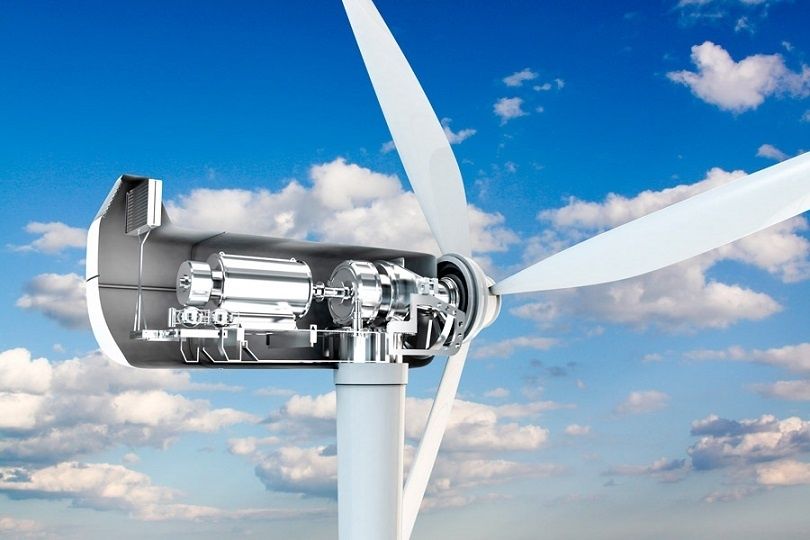 Närbild av vindturbinens generator och stora vita rotorblad mot blå himmel